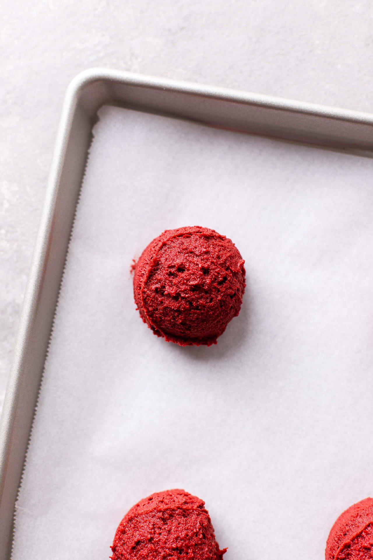 frosted red velvet cupcake cookies scoops of dough on parchment lined baking sheet