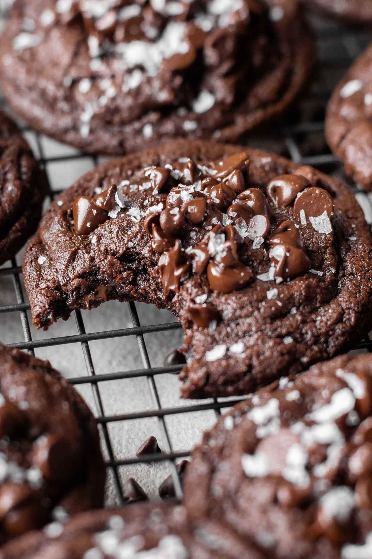 double chocolate chip cookies on wire rack with one missing bite