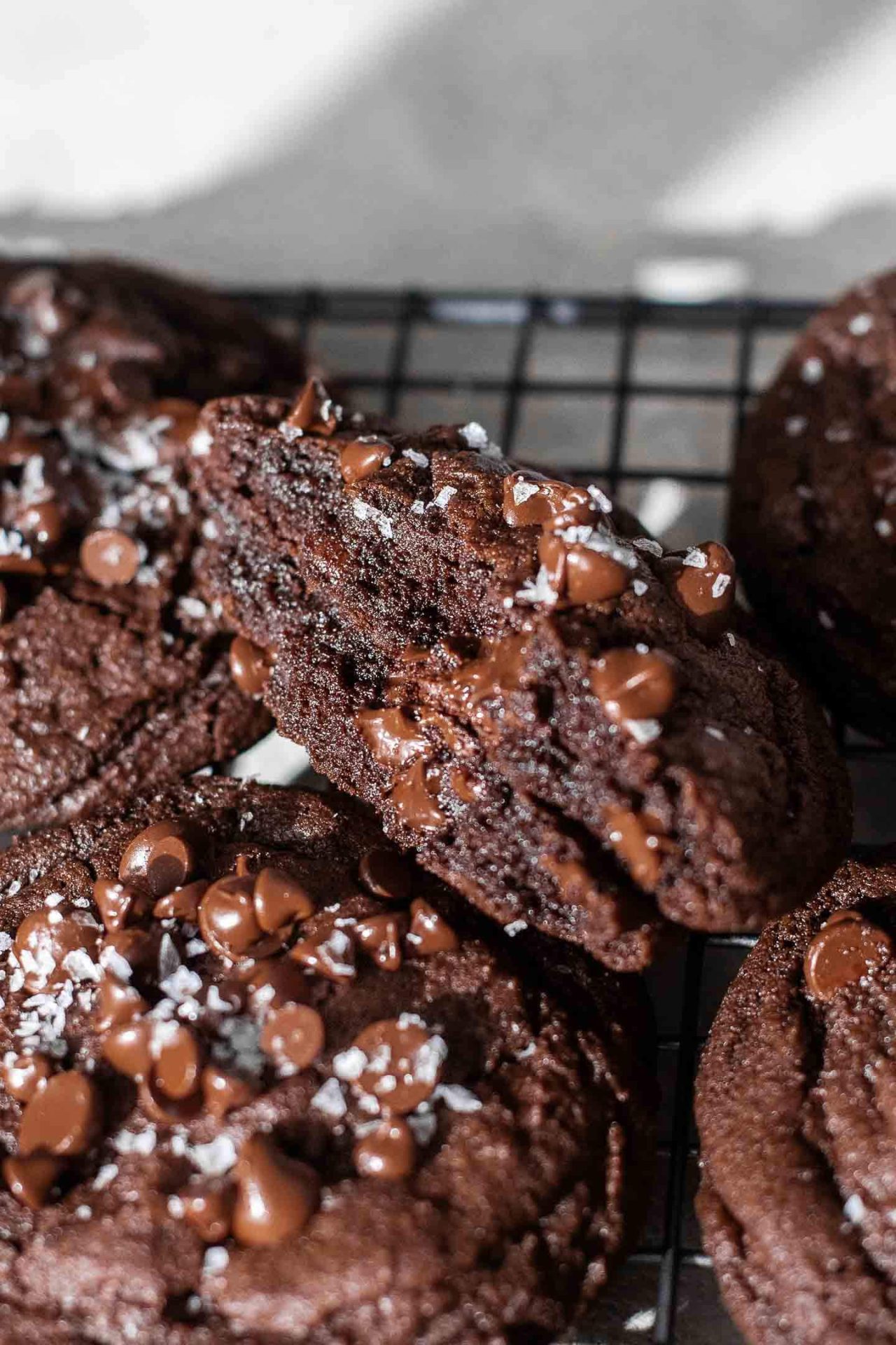 double chocolate chip cookies on wire rack with one cookie split in half