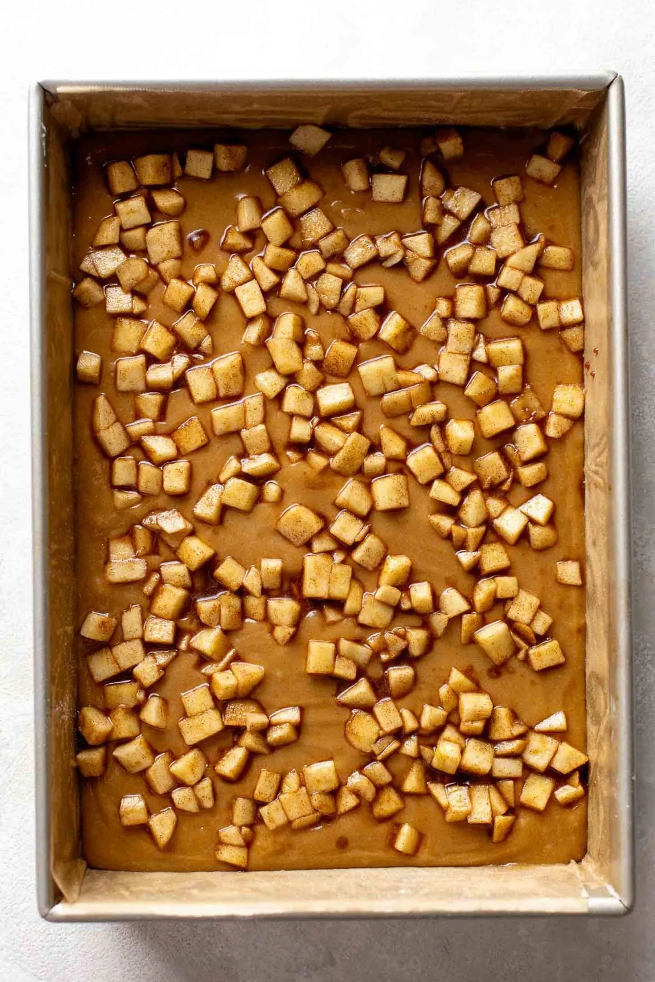 brown butter apple blondie batter in pan with spiced apples sprinkled on top