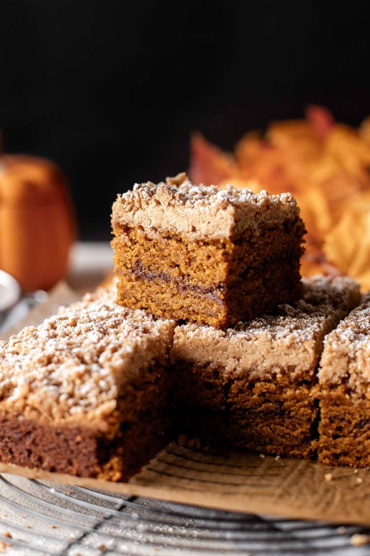 sliced pumpkin coffee cake on parchment lined wire rack with 2 slices stacked
